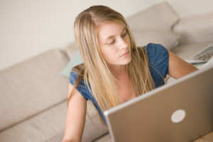 A blonde girl at home using a laptop computer